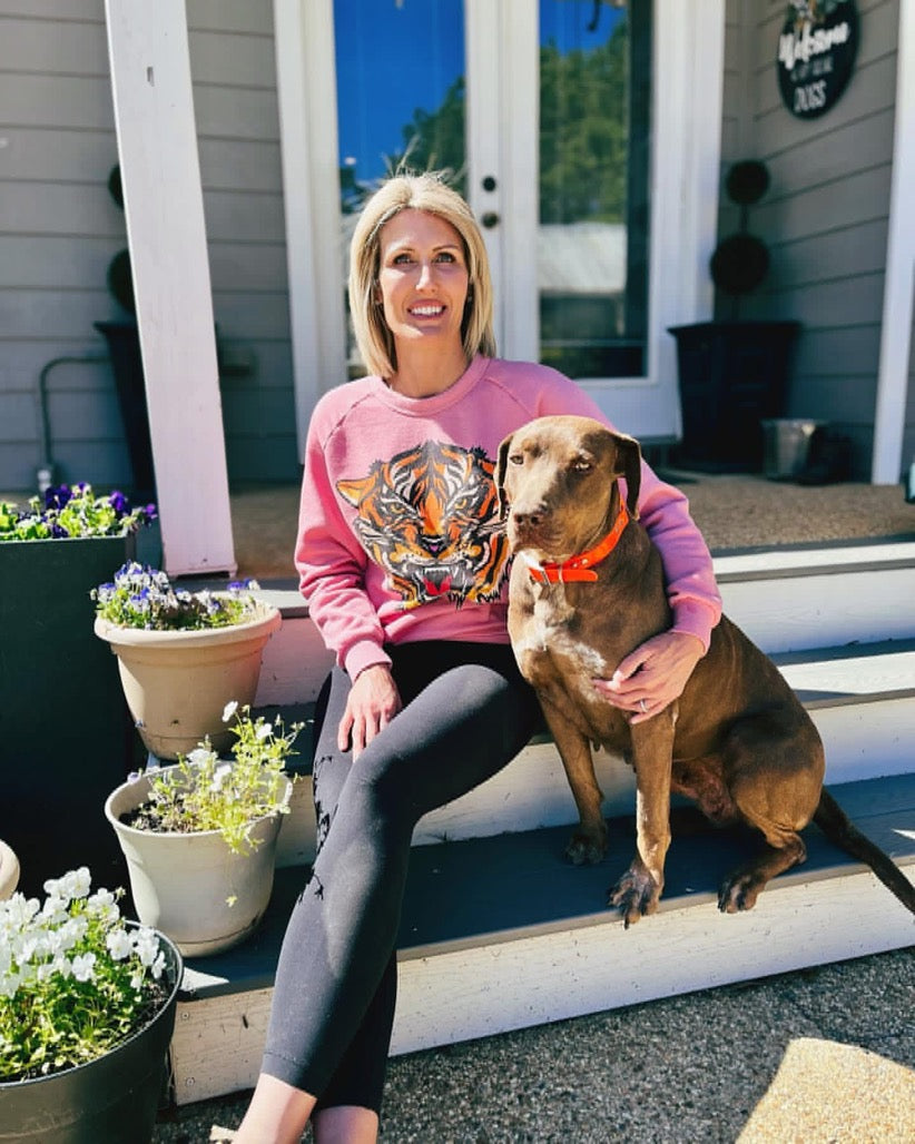 Smiling woman sitting on outdoor steps beside a chocolate-colored Catahoula Leopard Dog, capturing the strong bond and companionship between owner and dog